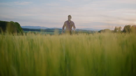 farmer walking through fields against mountains and rural landscape