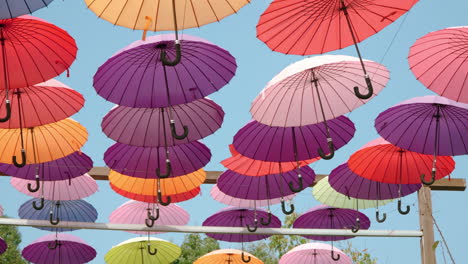 caminando bajo paraguas coloridos colgando en el aire arriba contra el cielo azul en la isla de hierbas en pocheon - decoración artística de la pasarela