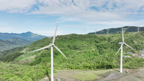 epic aerial footage of elongated white wind turbines atop rolling hills