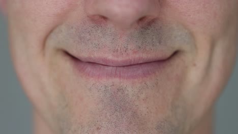 close-up of a man's mouth with stubble, transitioning from neutral to smiling