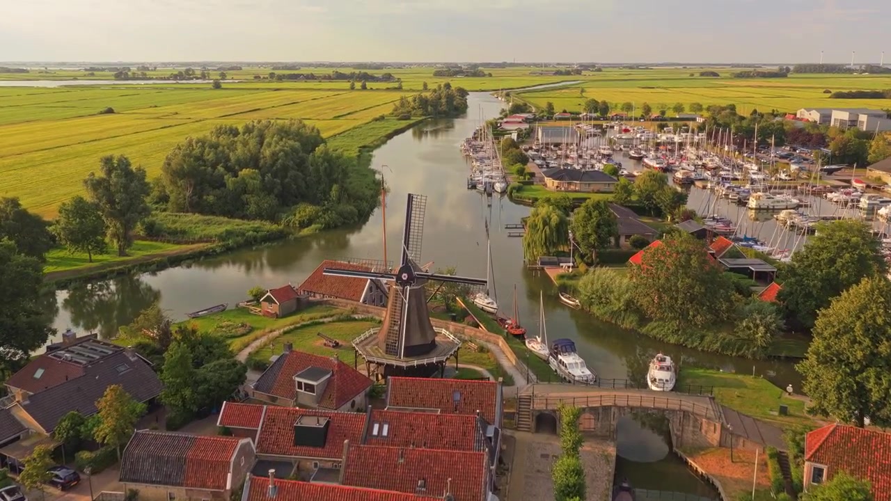 Luftfoto af en traditionel hollandsk landsby med kanal og vindmølle
