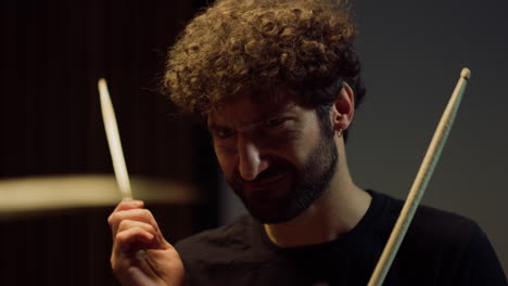 Drummer playing on drum kit in studio. Emotional male musician rehearsing indoor