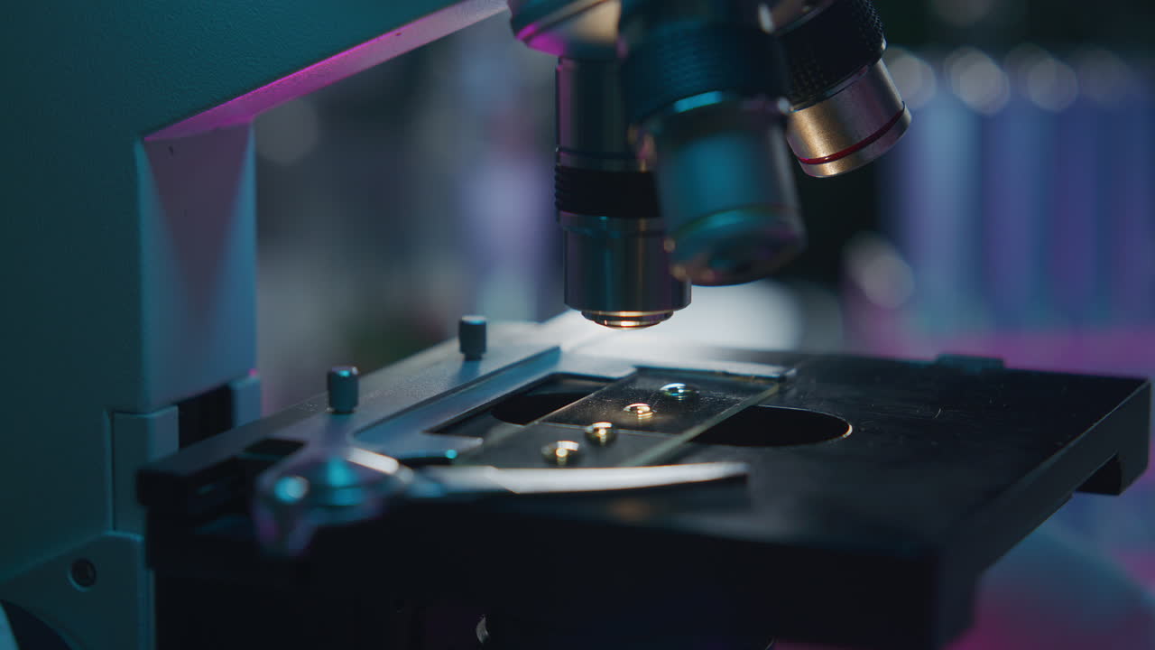 Close Up of Analyzing Specimen on Illuminated Slide under Microscope