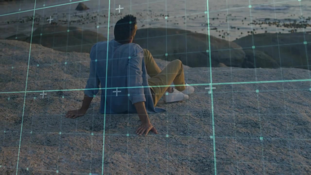 Mand sidder på kystklipper med udsigt over havet og digitalt gitteroverlay