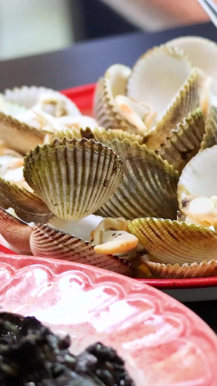 Person enjoying boiled clams with dipping sauce in Phuket, Thailand