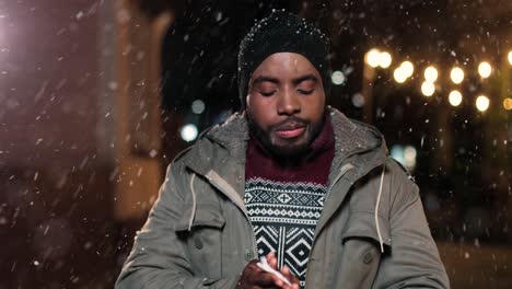 close-up view of sick african american man in grey coat blowing her nose on the street while it¬¥s snowing in christmas