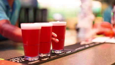 el camarero sirve bebidas rojas en un bar.