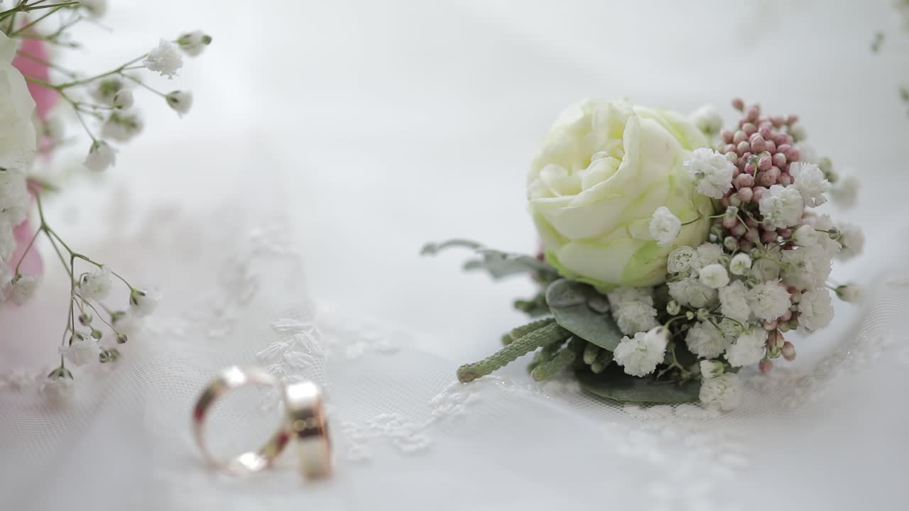 Bellissimi bouquet nuziali giacciono con le fedi nuziali vicino alla finestra su tende bianche.