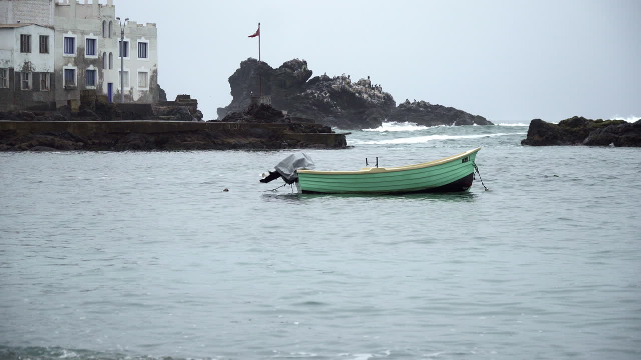 페루 리마 산 바르톨로(san bartolo)의 바위가 많은 해안을 따라 정박한 나무 청록색 배