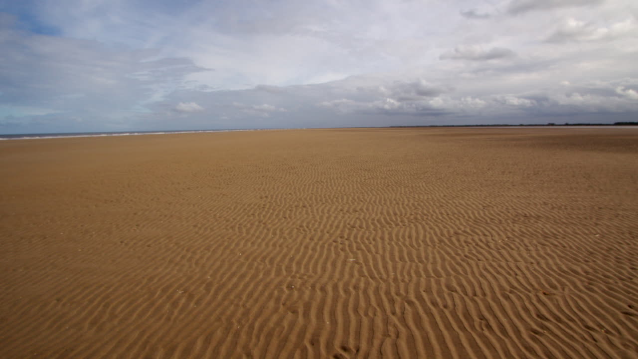 상위 3분의 1에 있는 폭풍우 구름과 함께 평평한 해변에서 파동의 추가적인 넓은