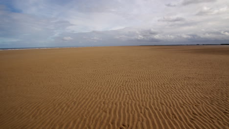 extra amplio disparo de ondas en una playa plana con nubes de tormenta en el tercio superior