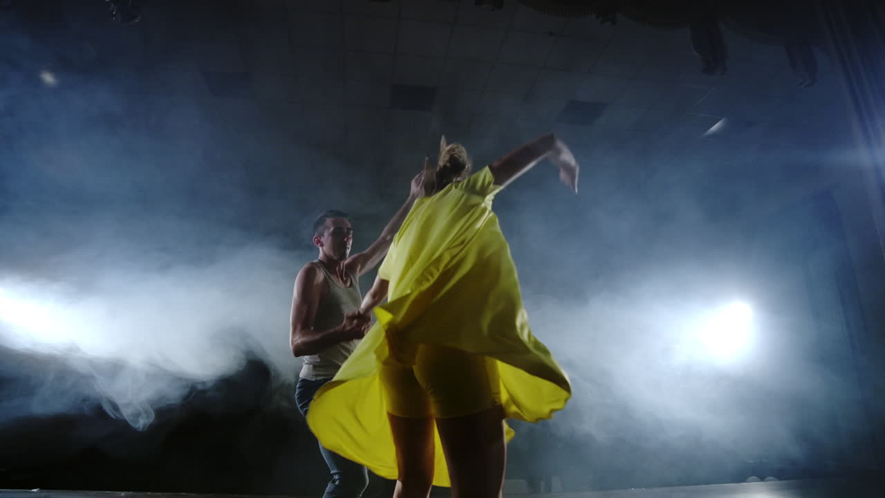 женская танцовщица прыгает на плечо своего партнера. акробатический танцевальный мюзикл на сцене в дыме. современный