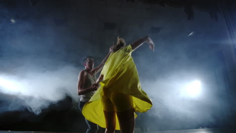 cámara de zoom una bailarina salta sobre el hombro de su pareja. musical de danza acrobática en el escenario en el humo. contemporáneo