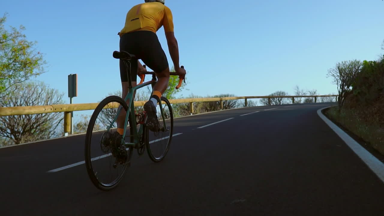 Engaging in outdoor exercise, a man cycles on a quiet morning road with his road bike. The slow-motion recording highlights the excitement of extreme sports