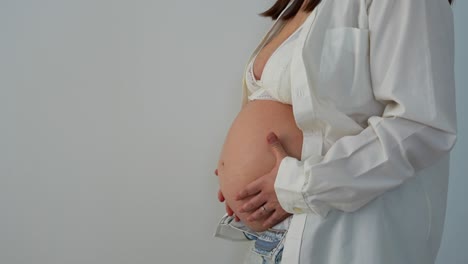 young woman with 36 weeks pregnant belly, medium shot on a white background