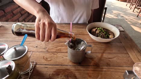 person mixing a drink with ice at a table