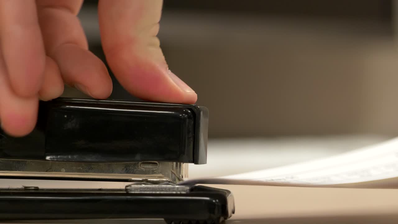 крупный план сбоку черного степлера, сшивающего листы бумаги в замедленном темпе