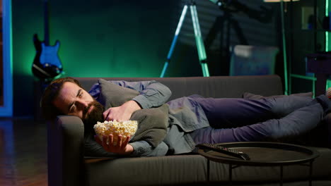 Sad person laying down, suffering from depression, watching TV to feel better