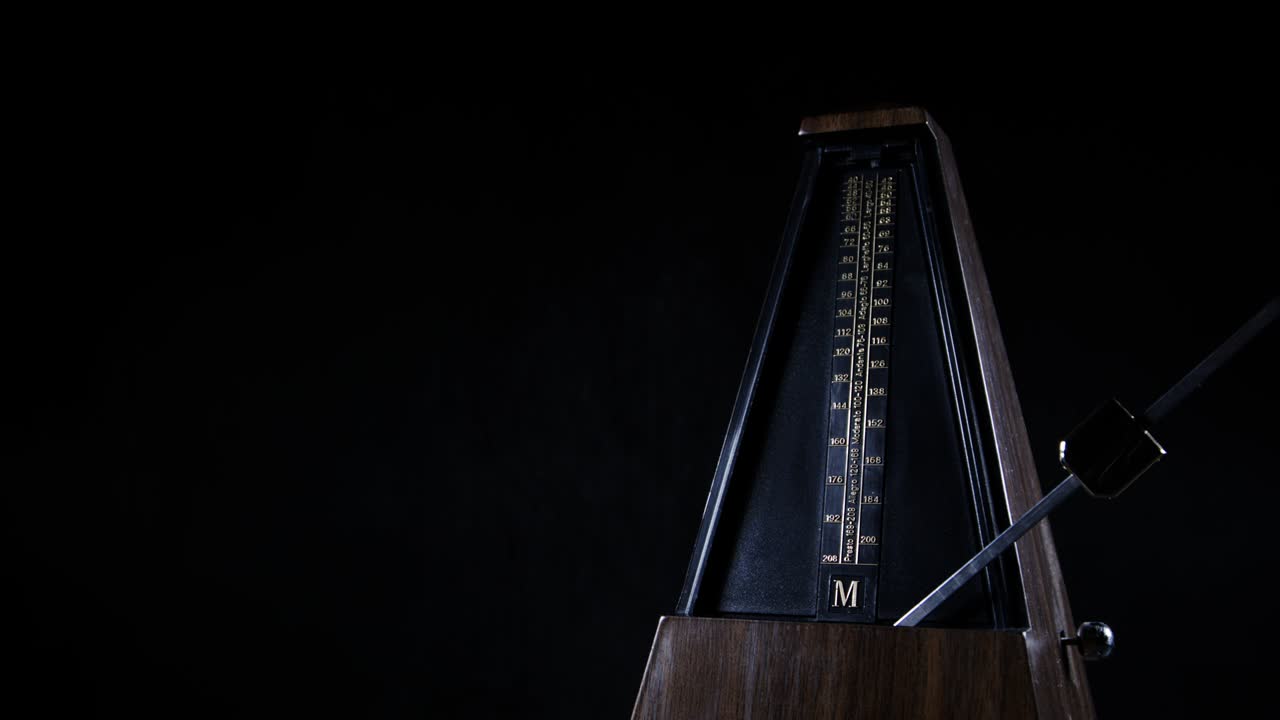 Metronomo con pendolo dorato che batte un ritmo lento su sfondo scuro