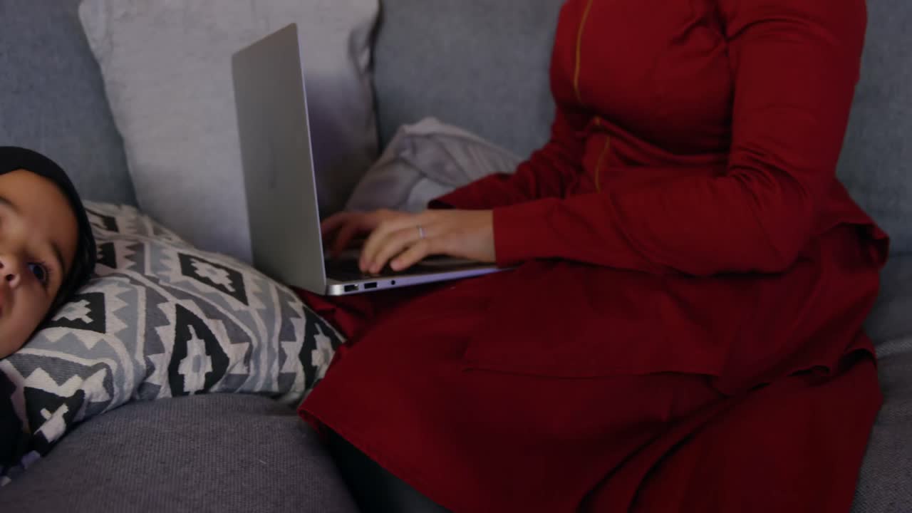 Mother using laptop while daughter watching television 4k