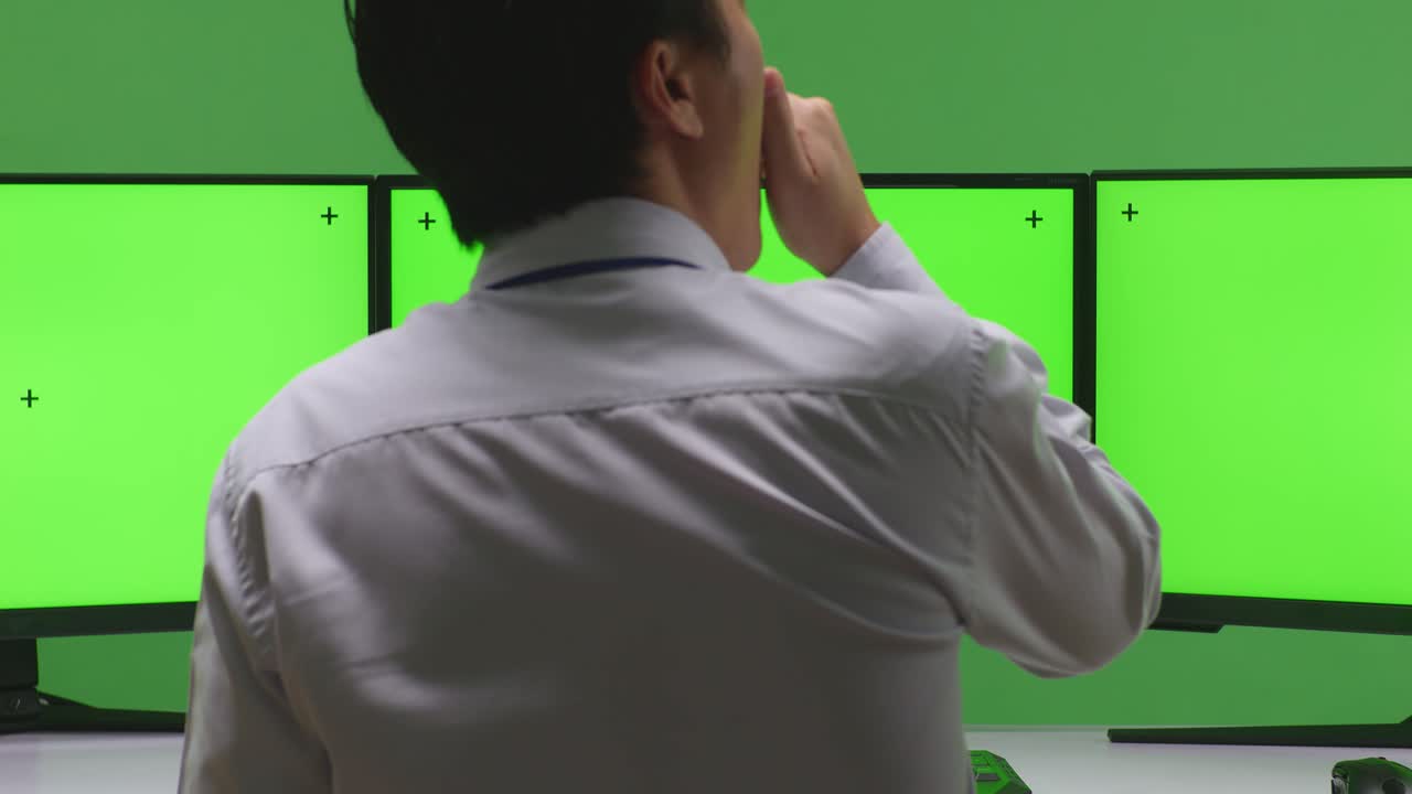 녹색 화면 녹음 세션 동안 트리플 모니터 작업 스테이션에서 사람