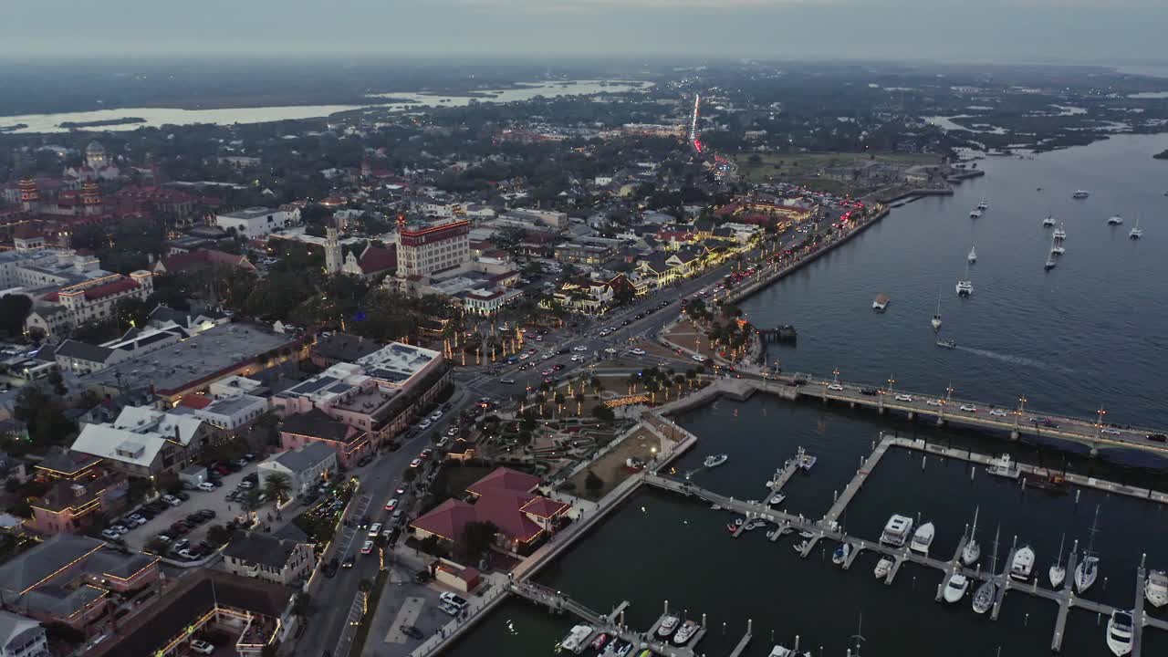 La vista aerea cattura il porto turistico di St. Augustine e le luci della città mentre cala il crepuscolo. Ideale per documentari di viaggio o studi urbani.