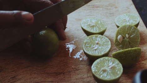 Beautiful close-up shot of an older latin woman cutting green lemons with pepa in half to prepare a sauce with onions in a stone kitchen inside a humble house in the highlands of Peru.