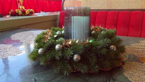 christmas wreath with candle in glass holder placed on table in pastry shop