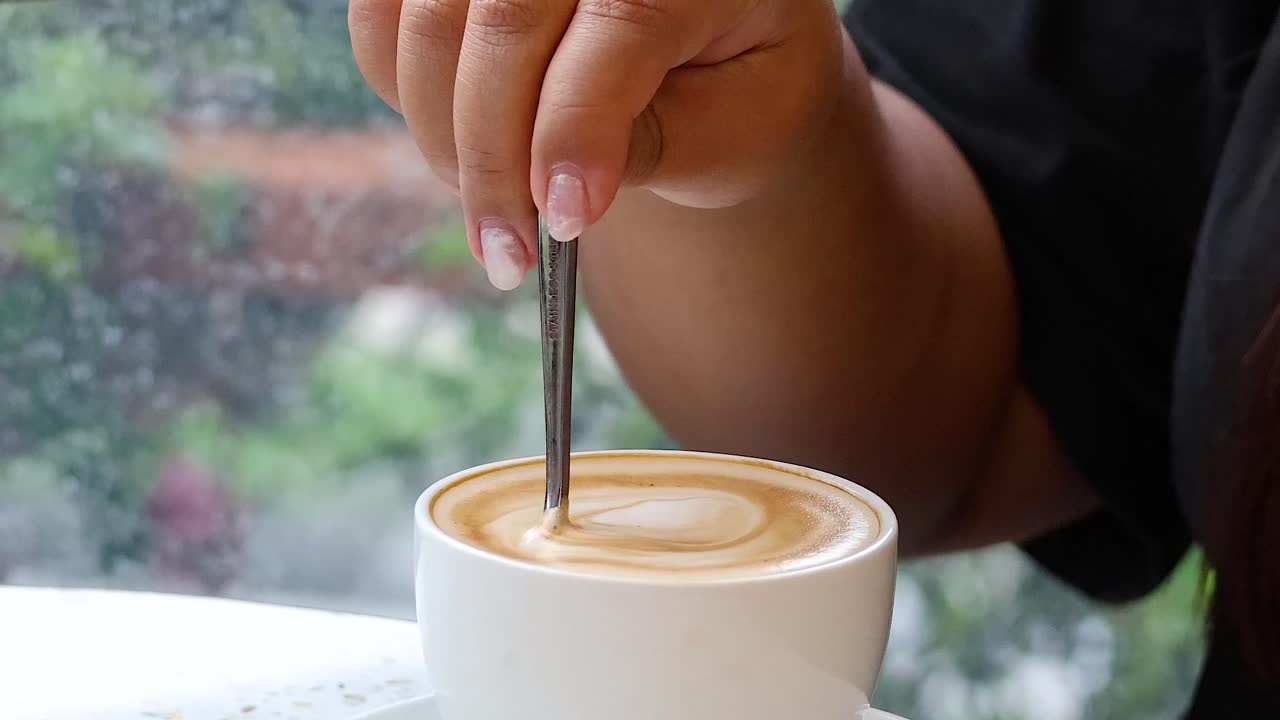 Person stirring coffee in a cafe