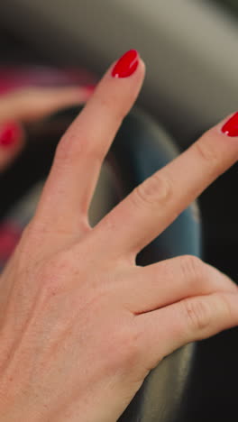 woman puts hands on steering wheel tapping fingers to dynamic music playing in car. elegant lady enjoys driving automobile in city closeup slow motion