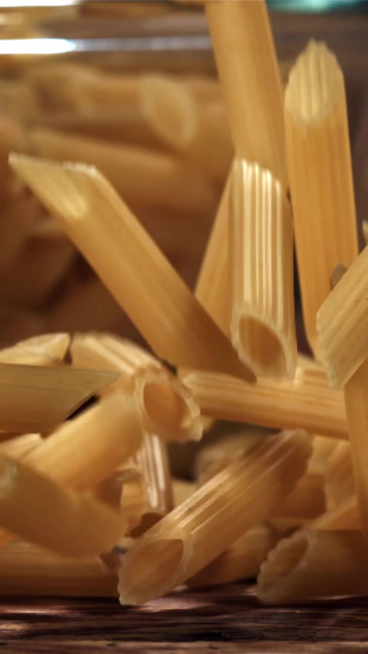 Penne che cadono al rallentatore su una superficie di legno