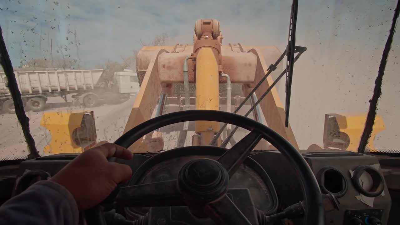 point of view of a bulldozer driver inside the cab while operating the mechanical shovel in a  stone quarry