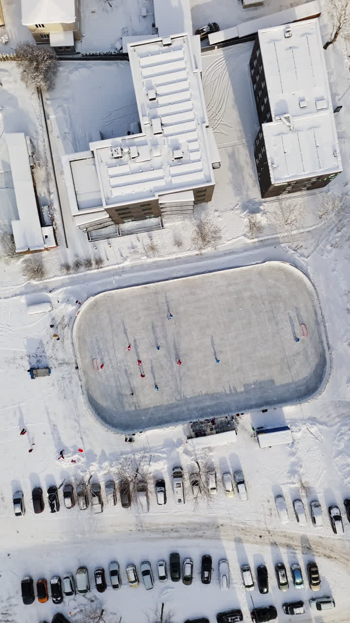 Portrait drone shot rotating above ice hockey game at a outdoor rink, winter day