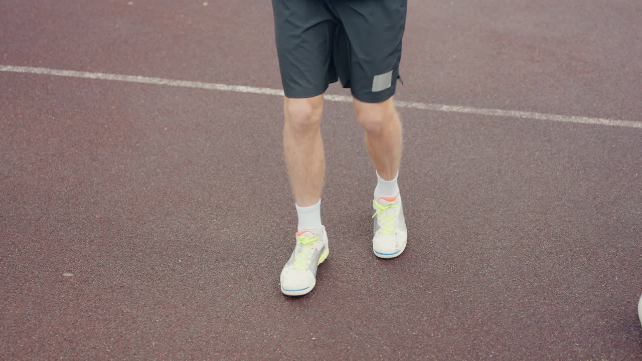 Regnerische Strecke, Quickstep-Aufwärmen und -Übungen, spielerische seitliche Schlurfbewegungen und Fokus auf die Trittfrequenz, Neon-Sneakers, die auf nasser Oberfläche tippen, blaue Windjacke in Bewegung, energiegeladene und technische Wiederholung