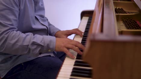 revealing-shot-of-caucasian-male-pianist-performing-on-a-vintage-piano-with-white-backround-slow-motion