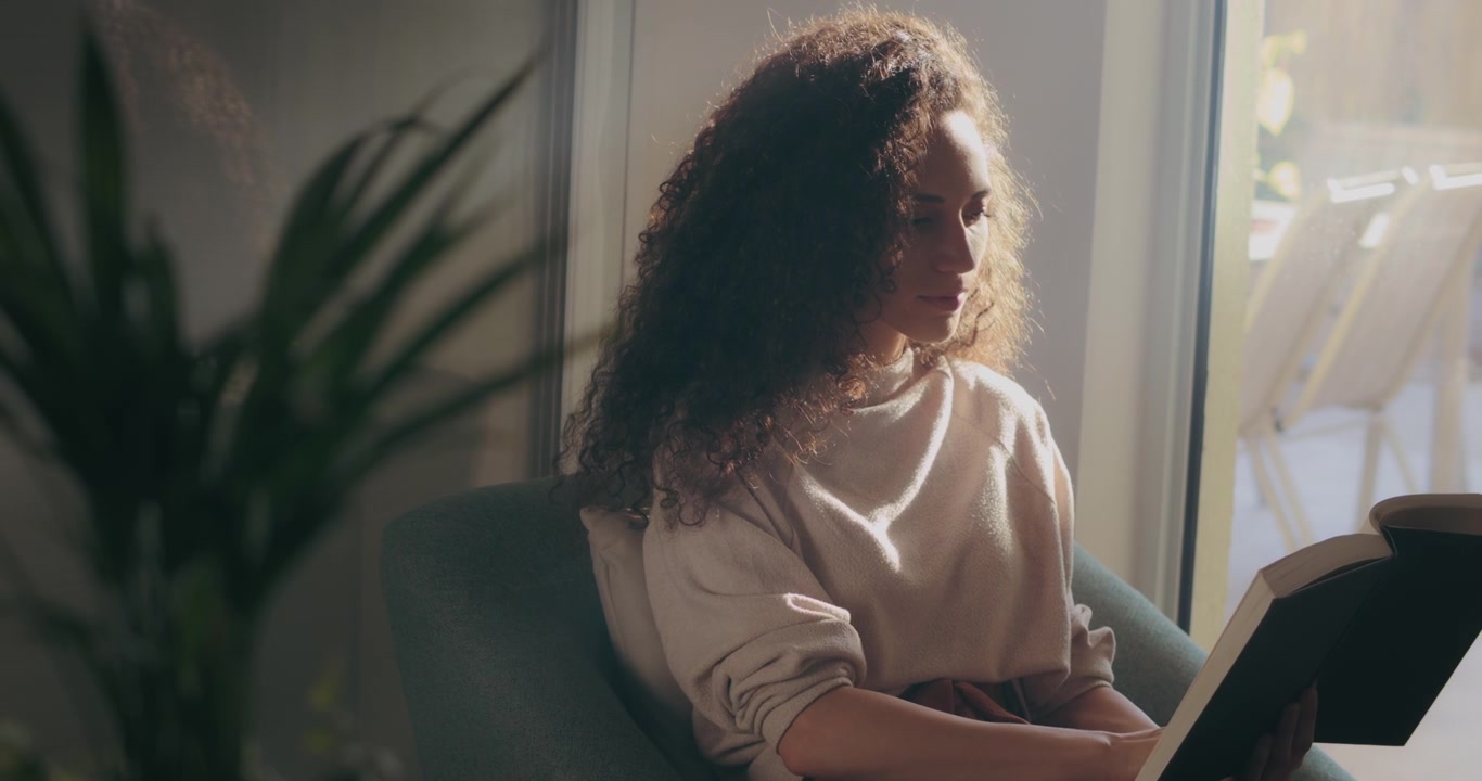 Ragazza con capelli ricci che legge un libro