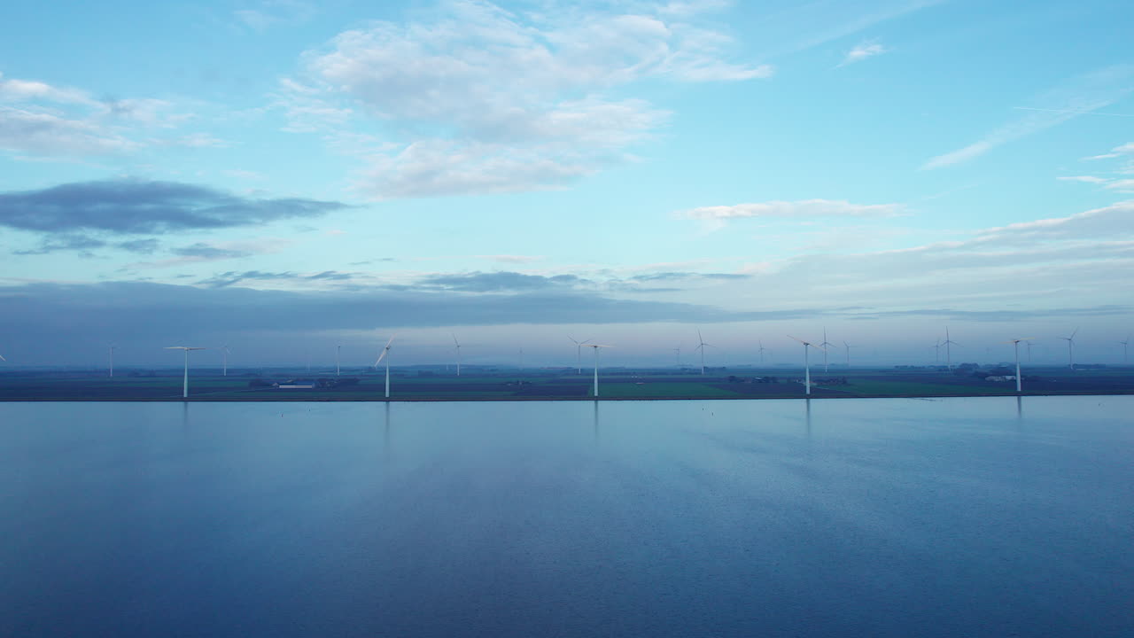 toma de camión de drones de la orilla del lago cubierta de turbinas eólicas en un día tranquilo sin viento