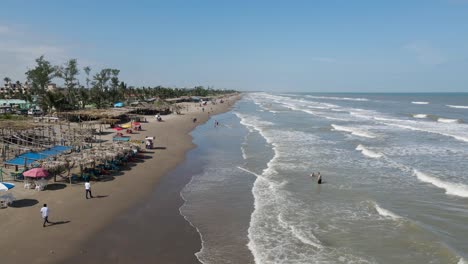 flying over the palapas and unrecognizable tourists on the beach at tecolutla, veracruz mexico