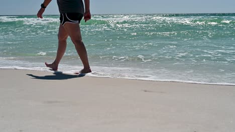 Women-walking-on-the-white-sandy-beaches-with-clear-emerald-waters-and-waves-on-the-Gulf-of-Mexico-on-a-bright-sunny-summer-day