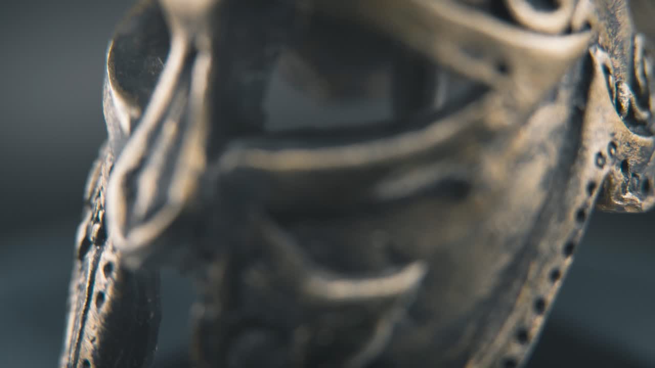 un macro de primer plano detallado de inclinación lenta hacia arriba disparo de un diseño de cara espartana, guerrero casco de bronce griego antiguo, en un soporte giratorio de 360, iluminación de estudio, hermosa profundidad de campo, movimiento suave de 4k