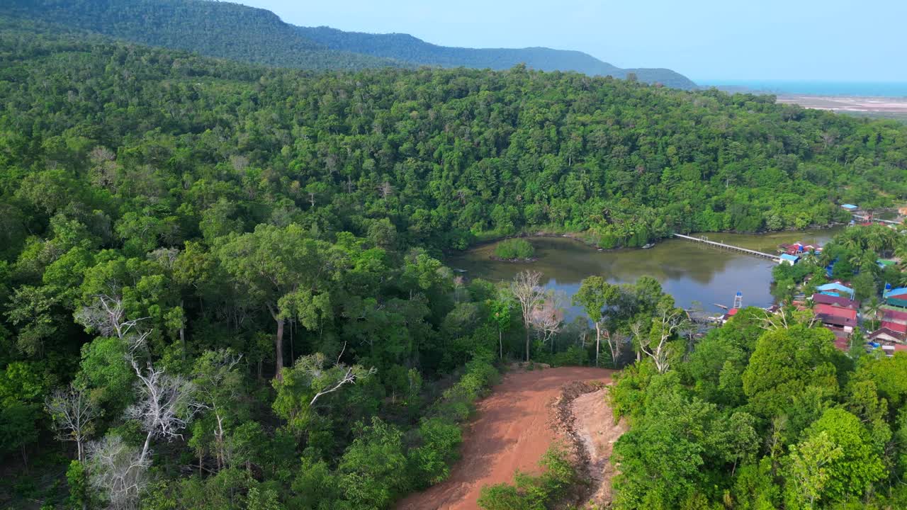 Koh Rong island, Cambodia, showcasing a fishing village with traditional houses on stilts, turquoise water, and lush vegetation. Spectacular aerial view flight panorama overview drone