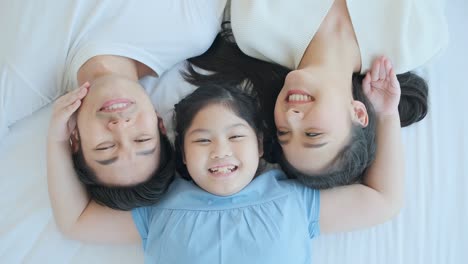 happy attractive young asian family portrait healthy harmony in life family day concept asian family man woman and little girl having good time together.top view bedroom mattress