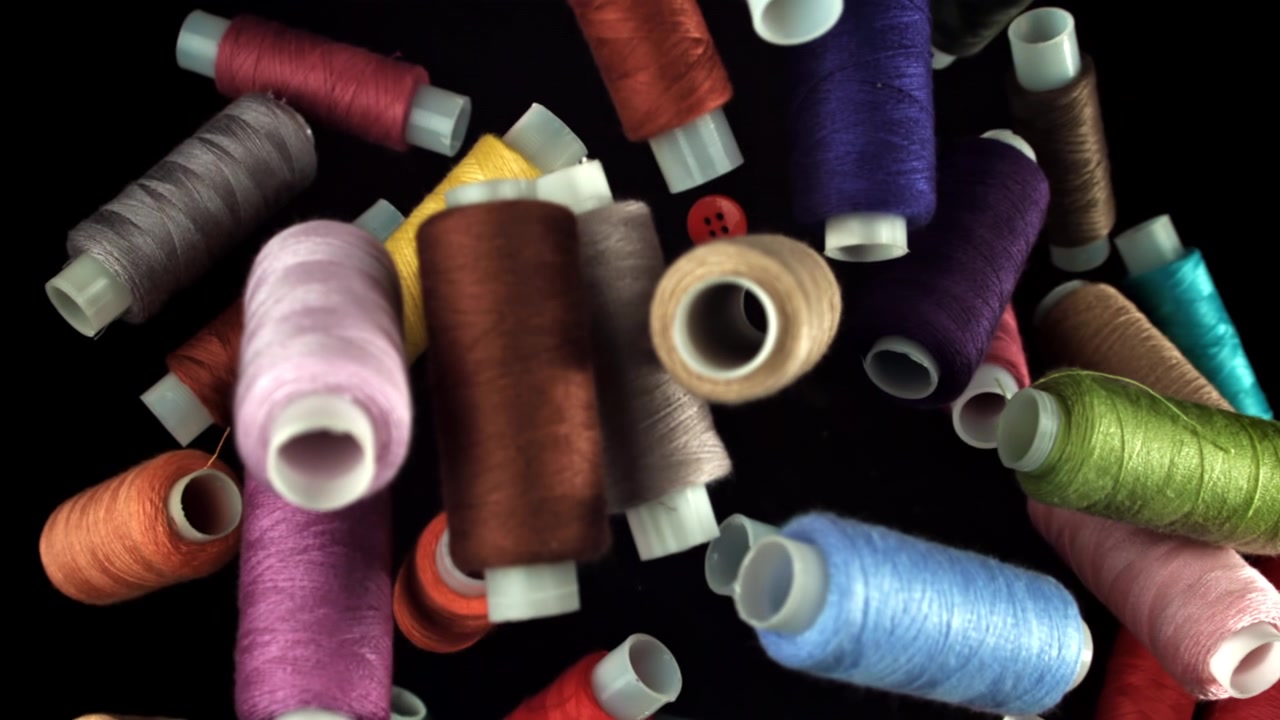 Overhead View of Colorful Sewing Threads and Button Zooming In