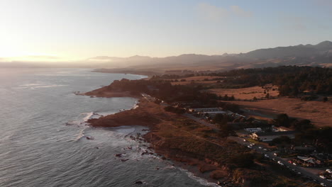 drone rotates around pacific coast highway as waves crash at golden hour