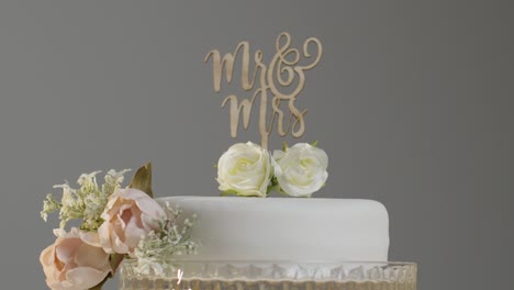 Primer-Plano-Del-Pastel-De-Bodas-En-El-Stand-Contra-El-Fondo-Gris-Del-Estudio-En-La-Recepción-De-La-Boda-2