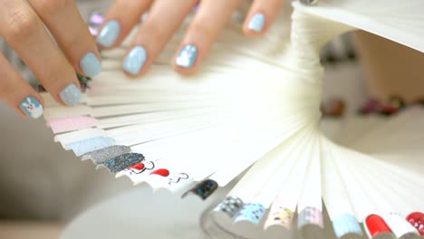 manicured hands and wheel of nail samples.