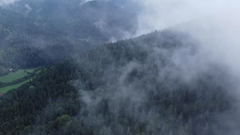 Aerial-view-of-a-dark-mountain-forest-with-big-moody-white-clouds,-in-Vosges,-France,-4K