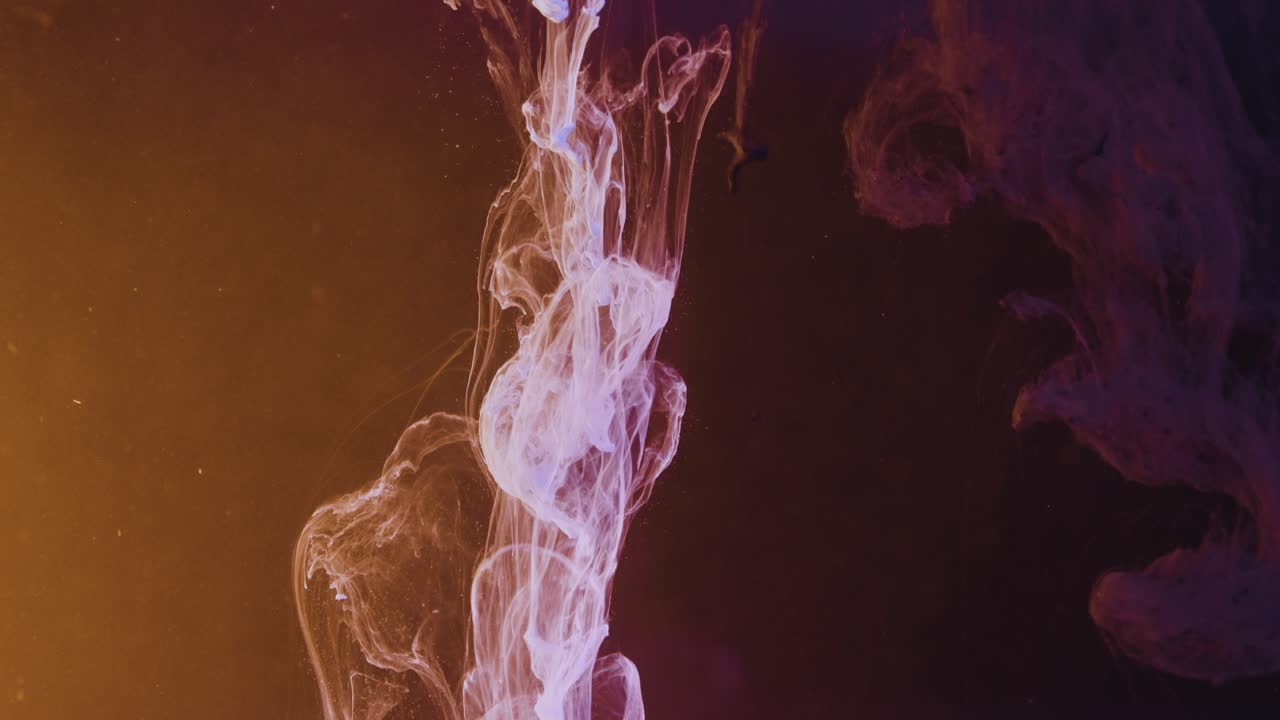 Purple And Orange Ink Droplets Cascade Down In Water On A Black Background