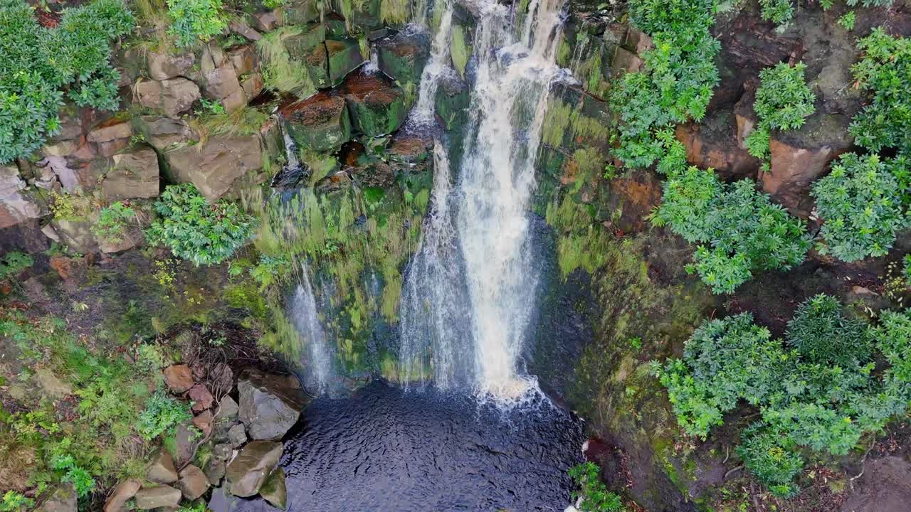 yorkshire moors sorprendente cascada, vista aérea captura el agua que fluye sobre grandes rocas en una piscina azul profundo, excursionistas cerca