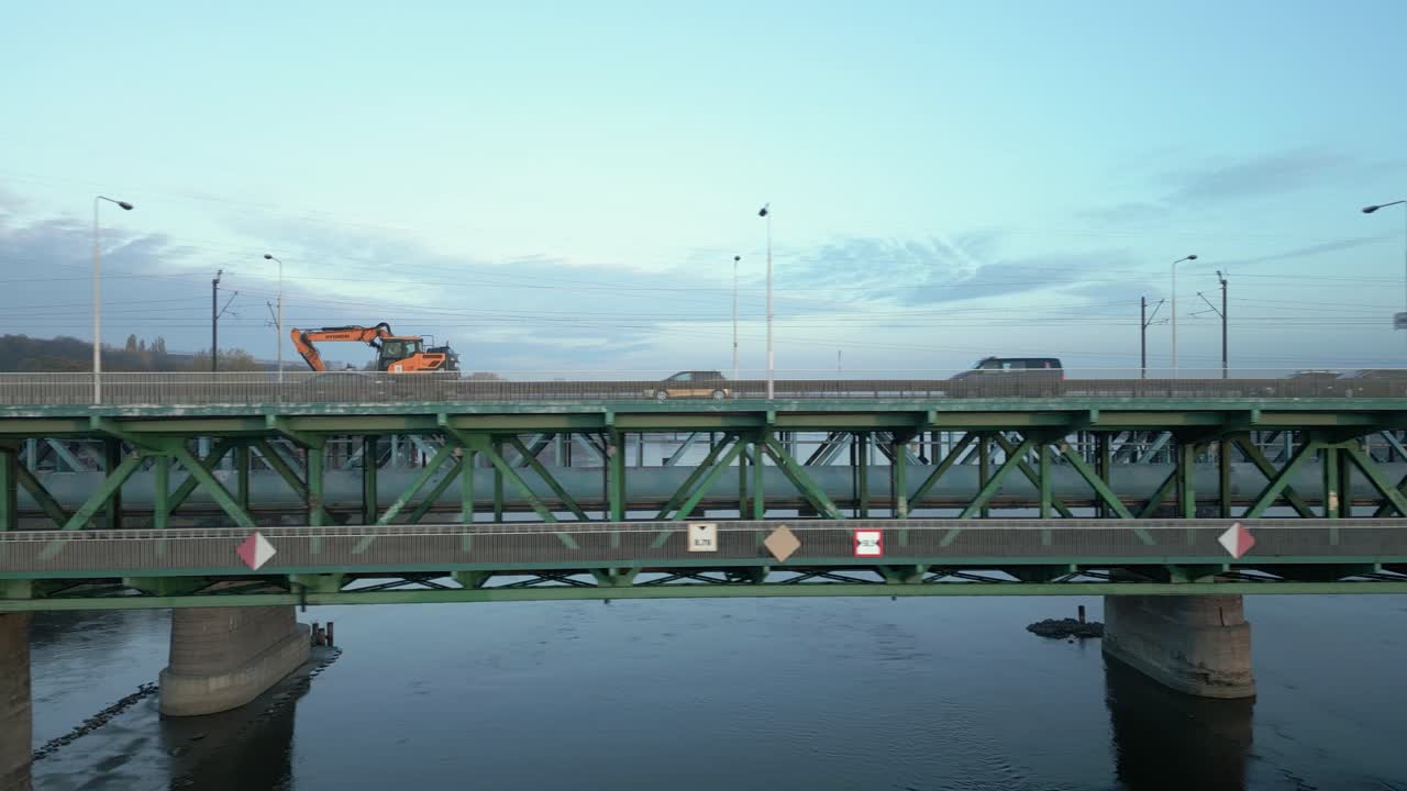 다리 위의 자동차가 느리게 움직이는 굴삭기를 추월합니다.